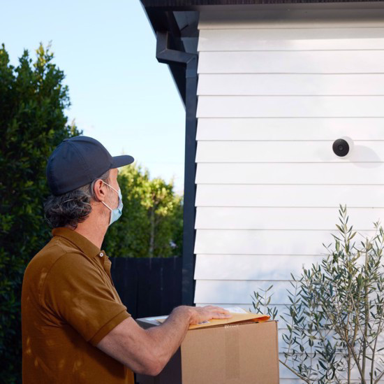 Google Nest Cam on the side of a house wall, capturing a delivery man.